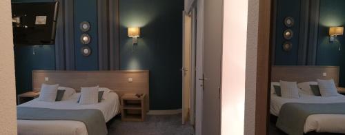 two beds in a room with blue walls at Hôtel Le Rohan Charme et Caractère in Pontivy