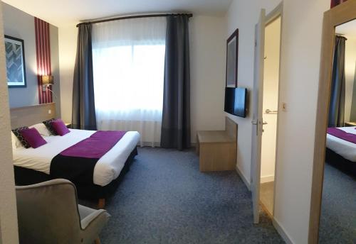 a hotel room with a bed and a television at Hôtel Le Rohan Charme et Caractère in Pontivy