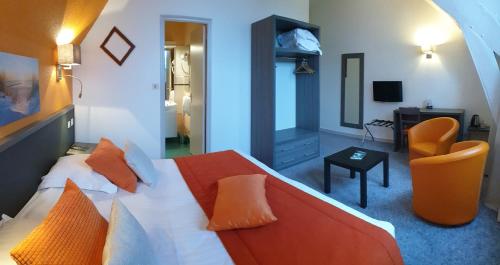 a bedroom with a bed with orange pillows at Hôtel Le Rohan Charme et Caractère in Pontivy