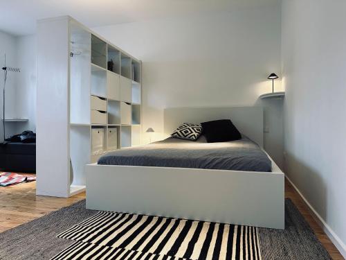 a white bedroom with a bed and a book shelf at Zentrum: Prater, Messe, WU in Vienna