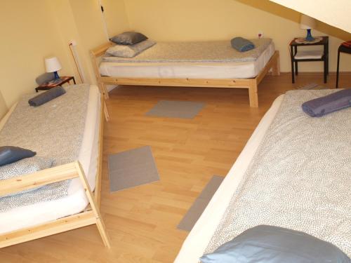 a room with three beds and a wooden floor at Gajó Kisduna Magánház in Dunavarsány