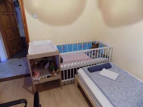 a small bedroom with a crib and a bed at Gajó Kisduna Magánház in Dunavarsány