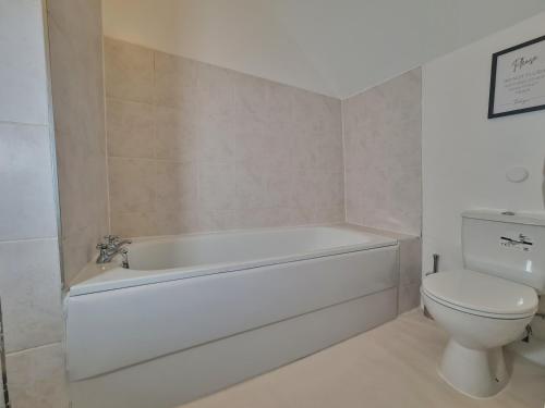 a bathroom with a white tub and a toilet at Lovely Large London Apartment Near Stratford in London