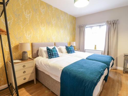 sypialnia z łóżkiem z niebieską pościelą i oknem w obiekcie Pengwern Bach w mieście Llanrwst