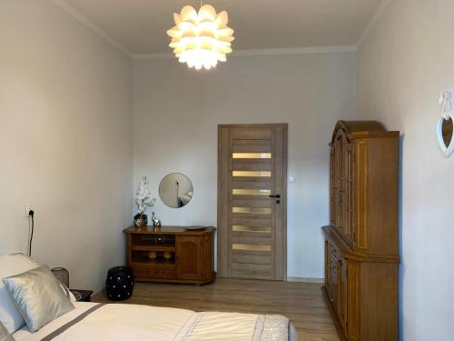 een slaapkamer met een bed, een dressoir en een kroonluchter bij Apartament Second Home in Strzelce Opolskie