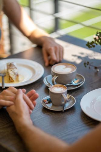 a person sitting at a table with two cups of coffee at Hotel Der Heinrichshof in Lagundo