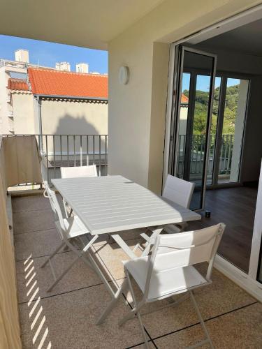 une table blanche et des chaises sur un balcon dans l'établissement Magnifique appartement climatisé de 87m², à 100m de la plage, à Antibes