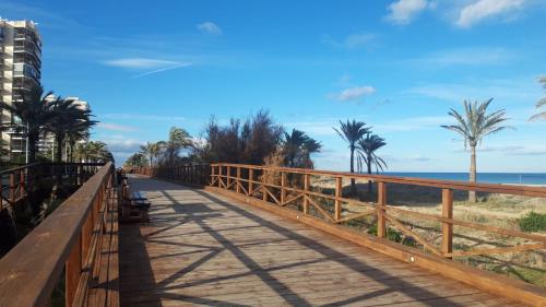 a boardwalk along the beach with palm trees and the ocean at Apartamento Aguilera in Gandía