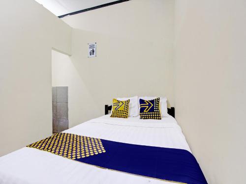a white room with a bed with yellow and blue pillows at SPOT ON 92220 Sari Laut in Glagah