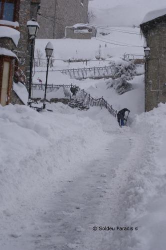una calle cubierta de nieve con una valla y una entrada cubierta de nieve en Soldeu Paradis Incles, en Incles