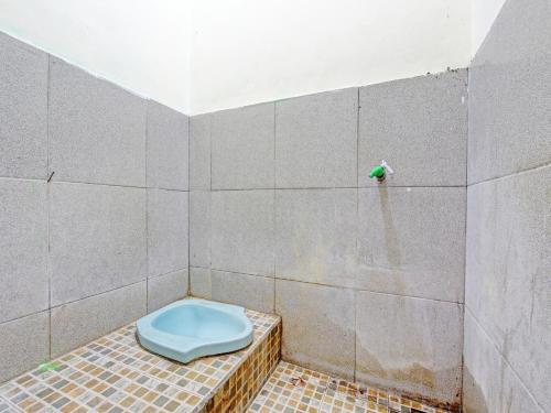 a bathroom with a blue toilet on a tiled wall at SPOT ON 92220 Sari Laut in Glagah