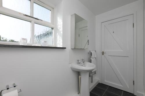 a white bathroom with a sink and a mirror at 15 Boscaswell Downs in Penzance
