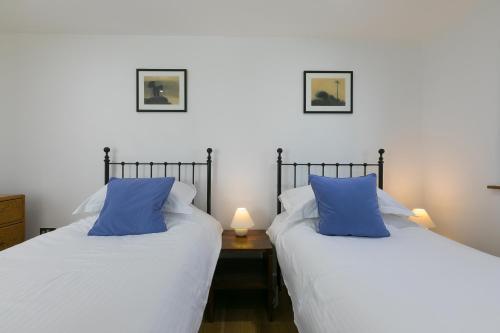 two beds with blue pillows in a room at 15 Boscaswell Downs in Penzance