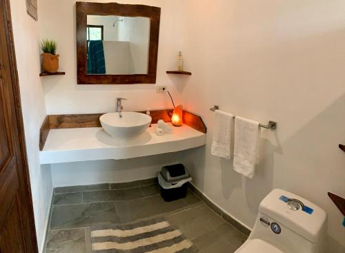 een badkamer met een wastafel, een spiegel en een toilet bij Casa Allegria in Tamarindo