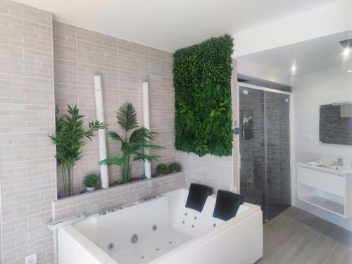 a bathroom with a white tub and plants on the wall at Espectacular apartamento con spa privado in Miami Platja