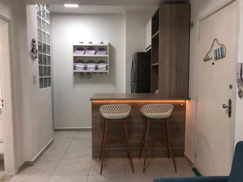 a kitchen with a counter and two stools at Apto em Santos com AR e Wi-Fi na rua da praia in Santos