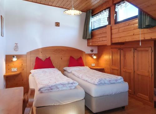 two beds in a room with wooden walls and windows at Piccola Suite sul Civetta in Colle Santa Lucia