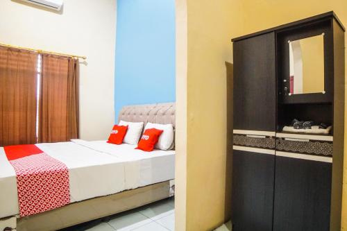 een slaapkamer met een bed en een dressoir met een spiegel bij SUPER OYO 92076 Sky Residence Cengkeh in Medan