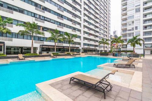 una piscina con bancos y un edificio en Departamento Real Suite, en Guayaquil