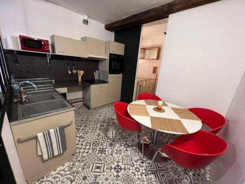une petite cuisine avec une table et des chaises rouges dans l'établissement « La Coquille Ancrée », à Dieppe
