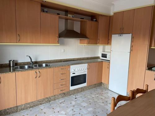 eine Küche mit Holzschränken und einem weißen Kühlschrank in der Unterkunft Casa turismo rural Becar in Corullón