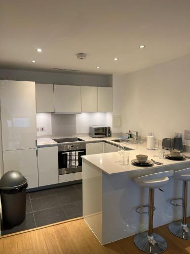 una cocina con armarios blancos y taburetes de bar en Stunning 1 bedroom Apartment in Croydon en Croydon