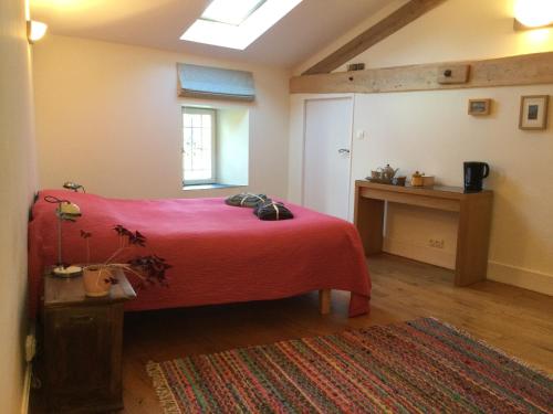 1 dormitorio con 1 cama con manta roja en Belle et spacieuse chambre d’hôtes avec piscine, en Savignac-de-Duras