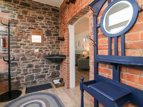 a room with a brick wall and a mirror at Hope House Stables in Tiverton