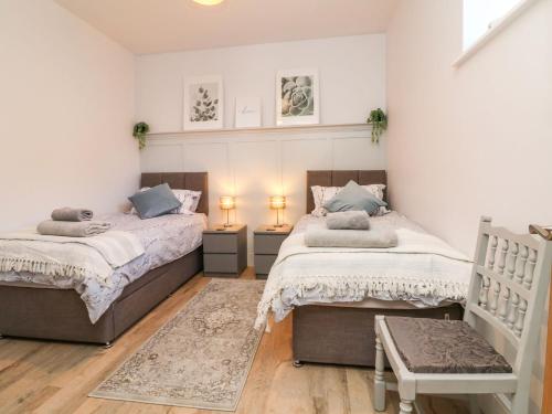 two beds in a bedroom with two lamps and a rug at Hope House Stables in Tiverton