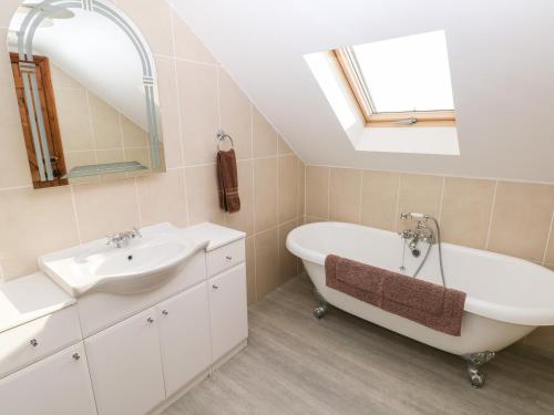 ein Badezimmer mit einem Waschbecken, einer Badewanne und einem Spiegel in der Unterkunft The Mill and Stable in Llansadurnen