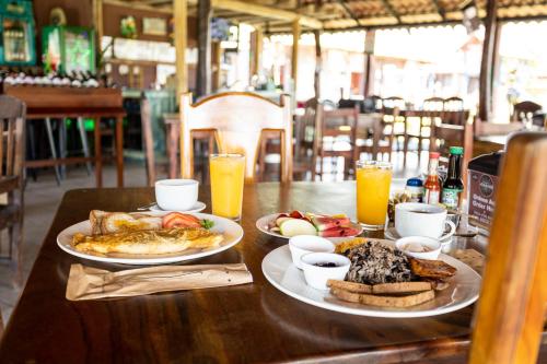 una mesa con dos platos de comida y zumo de naranja en Hotel El Rancho, en Quepos