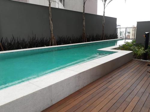 una piscina con terraza de madera junto a un edificio en Smart Studio Mobiliado na Vila Mariana, en São Paulo