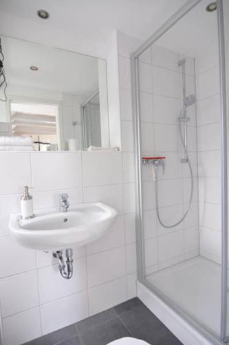 a white bathroom with a sink and a shower at Wertschätzer II - Unter der Wehme in Detmold