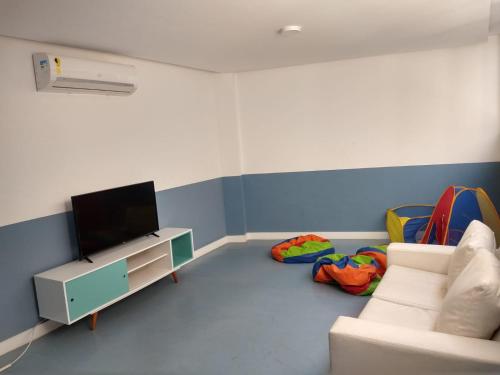 a living room with a couch and a flat screen tv at Apartamento no Golden Lake - pé na areia, agua de côco e cervejinha in Arraial do Cabo