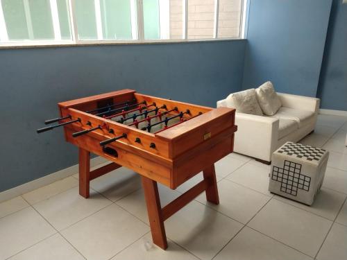 a wooden game table in a living room with a couch at Apartamento no Golden Lake - pé na areia, agua de côco e cervejinha in Arraial do Cabo