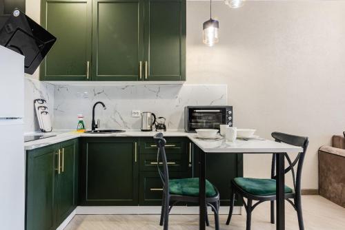 a kitchen with green cabinets and a table and chairs at Сердце города 1комн ЖК Молодёжный in Almaty