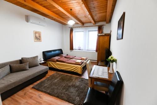 een woonkamer met een bank en een bed bij Kékszilva Vendégház in Pap
