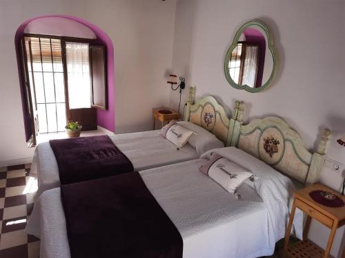 1 dormitorio con 1 cama grande y espejo en La Cata, en Aguilar de la Frontera