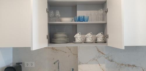 un armadio bianco con piatti, ciotole e bicchieri di Aldea Blanca Cute a Marbella
