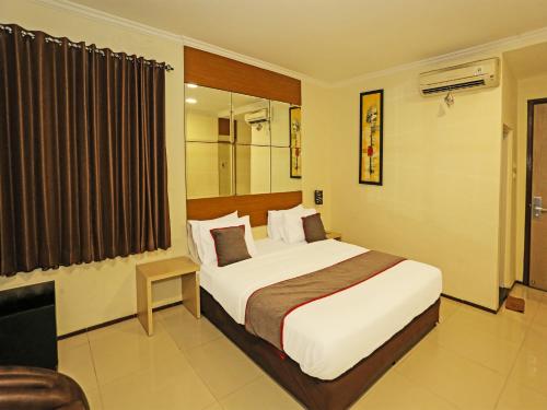 a hotel room with a bed and a television at Super OYO Townhouse OAK Hotel Fiducia Serpong in Serpong