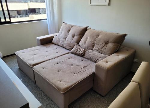 Sofá marrón en la sala de estar con ventana en EXCELENTE Apto Edifício Santorini, en Maceió