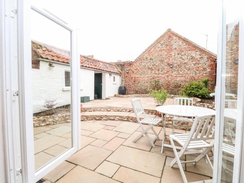 a patio with a table and chairs and a window at Springfield in Fakenham