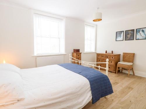 a bedroom with a white bed and two windows at Springfield in Fakenham