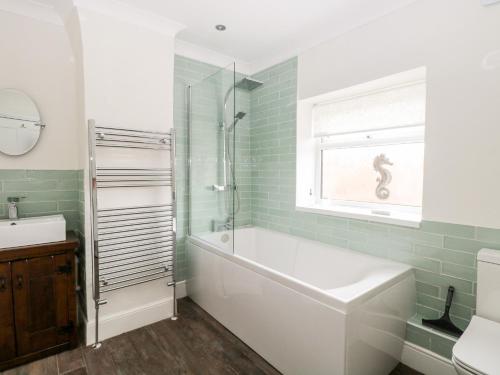 a bathroom with a tub and a sink and a window at Springfield in Fakenham