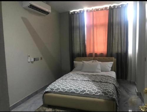 a bedroom with a bed and a window with curtains at Adonai Luxury Apartments Accra in Spintex