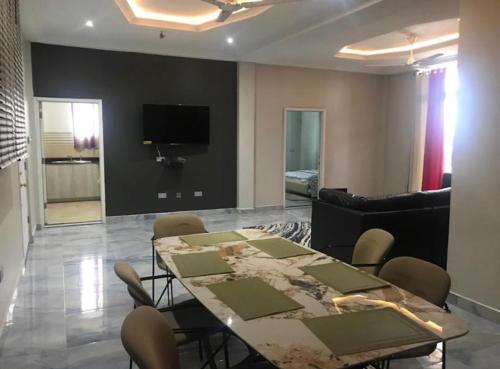 a dining room with a table and chairs and a television at Adonai Luxury Apartments Accra in Spintex