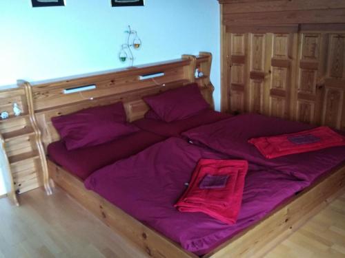 a large wooden bed with purple sheets and pillows at Pleasant Apartment in Zenting with Garden in Zenting