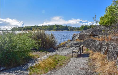 a bench sitting on a path next to a body of water at Beautiful Home In Ronneby With Sauna in Ronneby