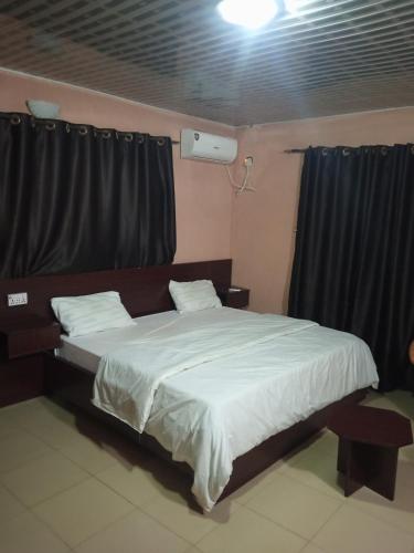 a bedroom with a large bed with black curtains at Greendale apartment and Lodge in Ibadan