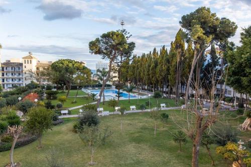 ein Park mit Bäumen und ein Schwimmbad in einer Stadt in der Unterkunft Enjoy La Carihuela Beach at 4 Min.Terrace & Pool. in Torremolinos